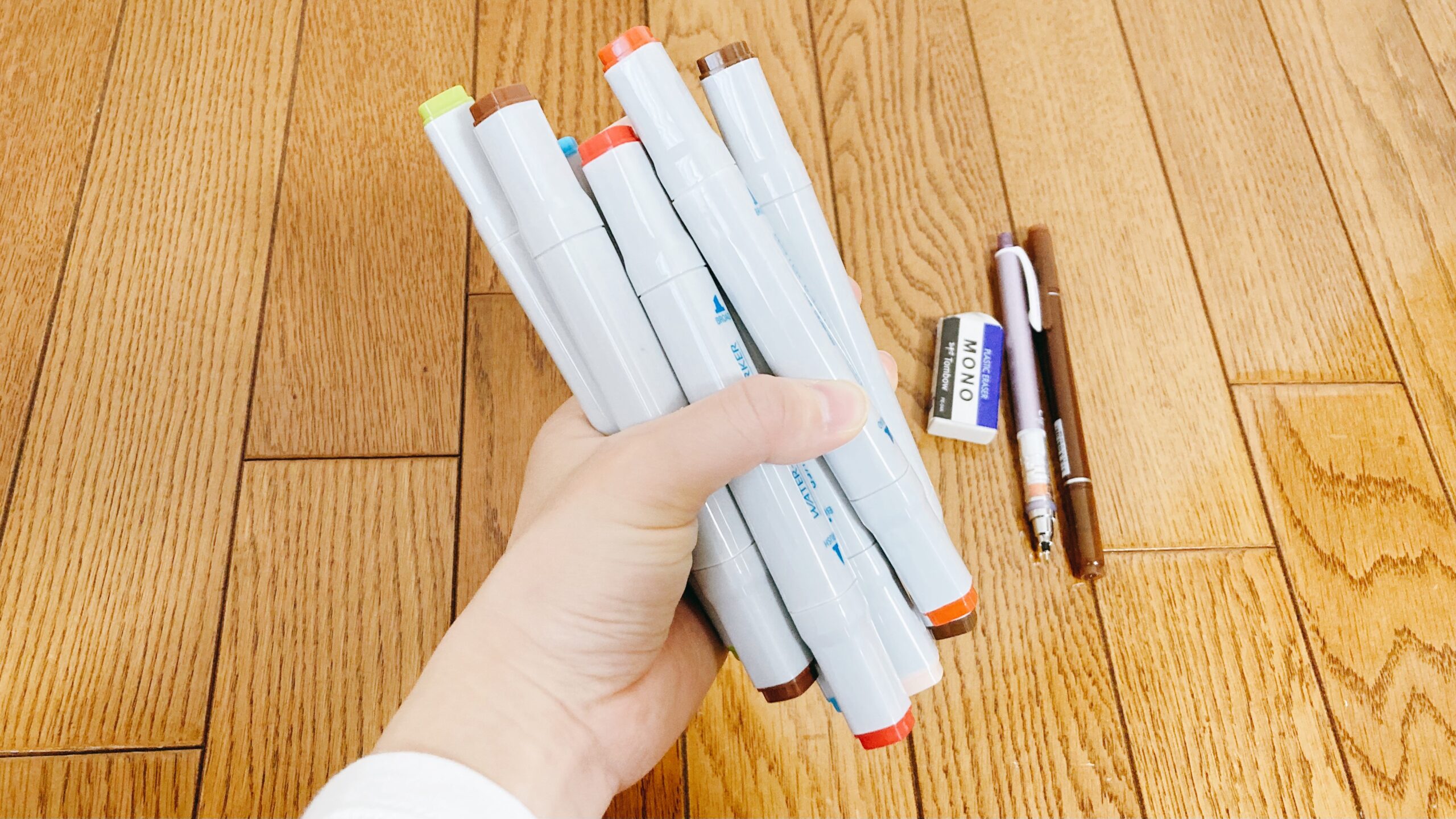 イラスト用のペン類を手で束にして握る様子